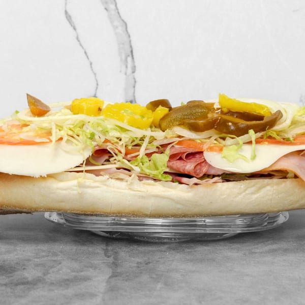 A large, fully loaded deli sub sandwich with various meats, cheeses, and vegetables.