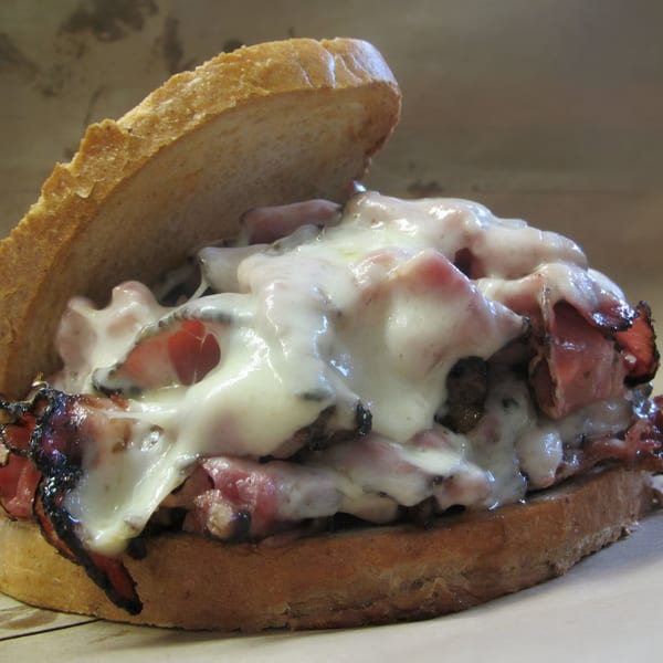 Close-up of a Koch's Deli roast beef sandwich with melted cheese on toasted bread.